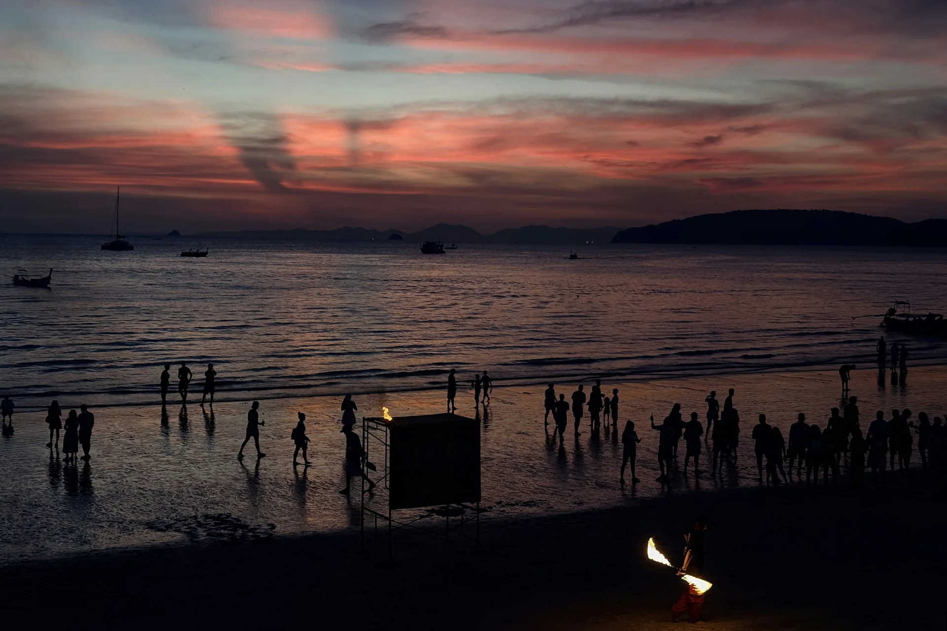 Ein polynesischer Künstler, silhouettiert vor einem Sonnenuntergang an einem hawaiianischen Strand